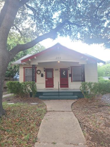 a small white house with red doors and a sidewalk at Cozy Home close to Downtown in San Antonio