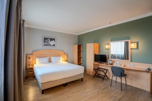 a bedroom with a bed and a desk with a computer at Tulip Inn Turin West Rivoli in Rivoli