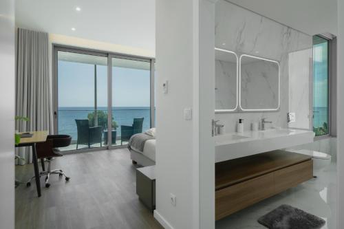 a bathroom with a sink and a bedroom with the ocean at OurMadeira - BeachFront in Madalena do Mar