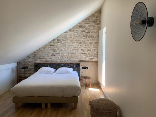 a bedroom with a bed and a brick wall at L'Annexe Deveney-Mars in Puligny-Montrachet