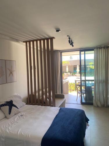 a bedroom with a bed and a view of a patio at Flat Garden 02-A - Beach Class Verano - Porto de Galinhas in Ipojuca