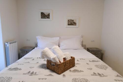 a bed with two towels in a basket on it at Sant'Orso Cozy Home in Cogne