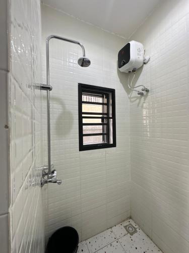 a white bathroom with a shower and a window at The NookHouse in Calabar