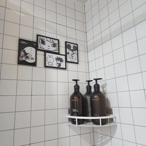 a shelf with four bottles on a white tiled wall at COZY stay in Seoul