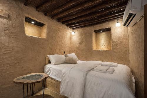 a bedroom with a bed and a table and two windows at بيت العريش Arish house in Sayq