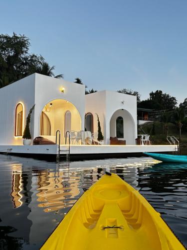 a yellow kayak in front of a house on the water at Heaven Raft Erawan Floating Resort Romantic River View in Ban Mong Lai