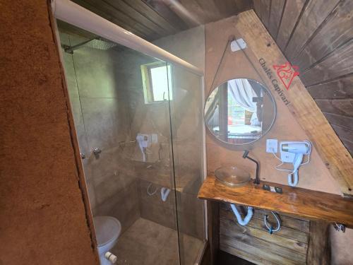 a small bathroom with a shower and a mirror at Chale Capivari Estrela in Campos do Jordão