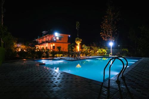 a swimming pool in front of a house at night at Corbett Nature Walk - Forest View Swimming Pool Retreat in Rāmnagar