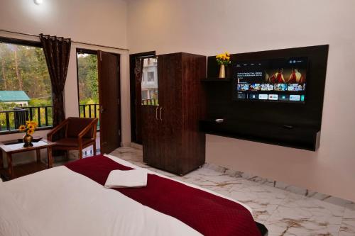 a bedroom with a bed and a television on the wall at Corbett Nature Walk - Forest View Swimming Pool Retreat in Rāmnagar