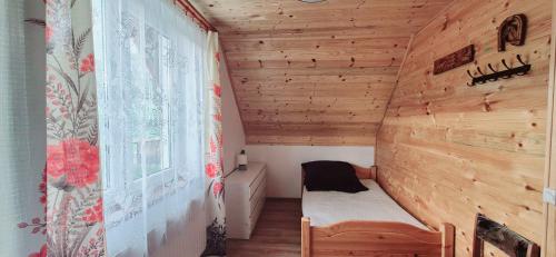 a small room with a bed in a wooden house at Domek Na Hawajach in Polana