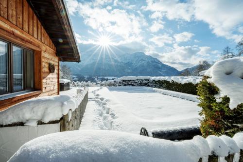 a snow covered house with a hot tub and the sun at Luxus Ferienhaus Salzburg Chalet mit Pool, Sauna, Whirlpool, Kamin in Grossgmain