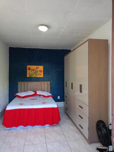a bedroom with a large bed with a red blanket at Hospedaria D' Gabi in São Pedro da Aldeia