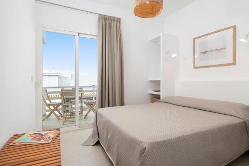 a bedroom with a bed and a balcony with a table at Apartaments S'Estanyol in La Savina