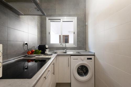 a kitchen with a sink and a washing machine at Apartaments S'Estanyol in La Savina