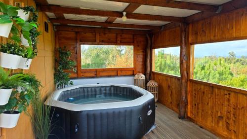 a jacuzzi tub in a room with two windows at Pura - Home in Nature in Oliveira do Hospital