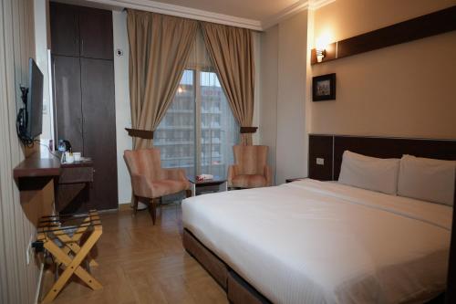 a bedroom with a bed and a desk and a window at Ream Hotel Amman in Amman