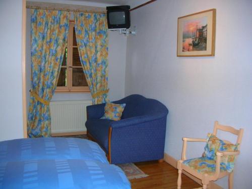a bedroom with a blue chair and a window at Hotel-Restaurant du Windstein in Windstein