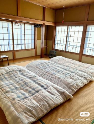 a large bed in a large room with windows at ロッヂ 雪ん子 in Yuzawa