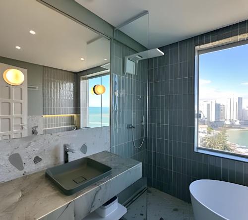 a bathroom with a sink and a toilet and a window at Guarapari Center Aparts in Guarapari