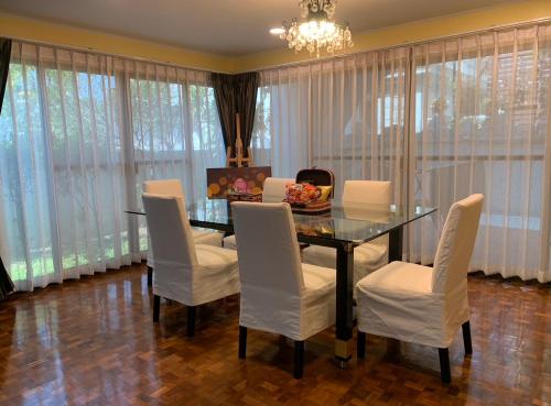 a dining room with a glass table and white chairs at Newly-renovated Modern Private Thai Villa with Swimming Pool in Ban Khlong Samrong