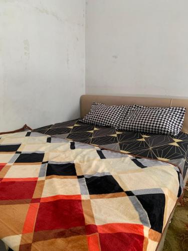 a bed with a colorful blanket and a pillow on it at Herald homestay wonosobo in Wonosobo