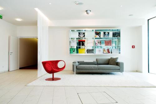 a living room with a couch and a red chair at Casinohotel Velden in Velden am Wörthersee