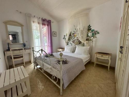 a bedroom with a white bed and a table at Achladies Cottages in Achladies