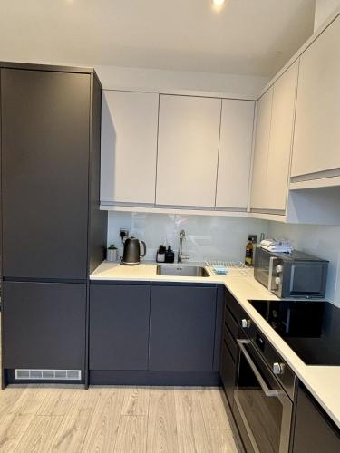 a kitchen with white cabinets and a sink at 6 Aviv Place in Addlestone