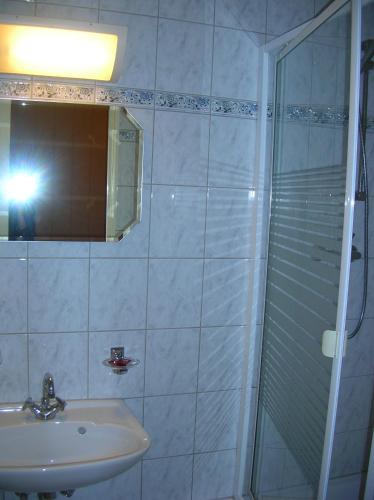 a bathroom with a sink and a shower with a mirror at Hotel-Restaurant du Windstein in Windstein