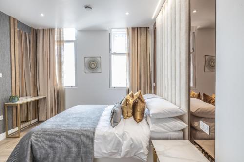 a bedroom with a bed with white sheets and gold shoes at The Pocklington Aparthotel - Luxury 1 & 2 Bed Serviced Apartments, City Centre, Perfect For Families, Contractors and Businesses in Leicester