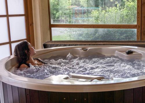 a woman in a hot tub with a window at Domaine des Epinettes in Saint-Romain-de-Jalionas