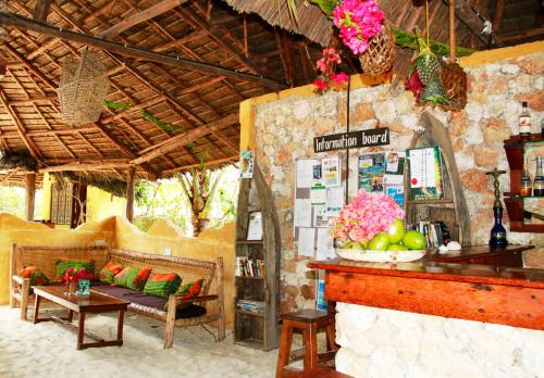 um quarto com um sofá e uma mesa com flores em Demani Lodge Zanzibar em Paje