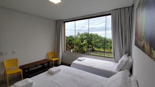 a hotel room with two beds and a large window at Pousada Real in Caldas Novas