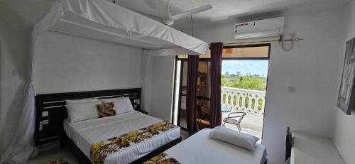 a bedroom with two beds and a balcony at Becky Homes Diani Beach - 2BR with AC & Pool in Diani Beach