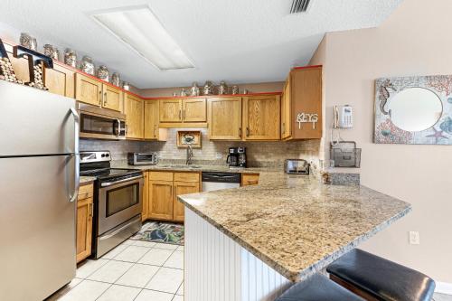 a kitchen with wooden cabinets and stainless steel appliances at Phoenix 6 Unit 1209 in Orange Beach