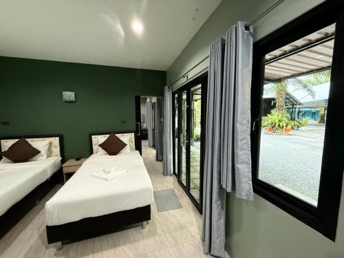 a bedroom with two beds and a large window at Farinda Resort in Phangnga