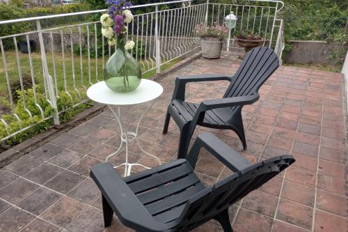 two black chairs and a table with a vase of flowers at Villa le Roche du Ris - 10-12 personnes in Baraize