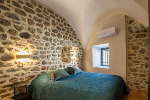 a bedroom with a blue bed in a stone wall at Domaine le C4 - restaurant et gîte d'exception familial avec terrasse Ardèche in Casteljau