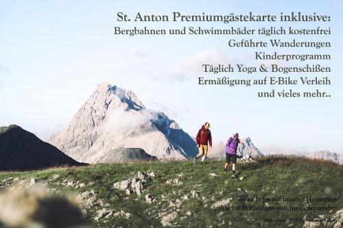 two people walking on a hill with a mountain in the background at ArlBerglife Ferienresort in Pettneu am Arlberg