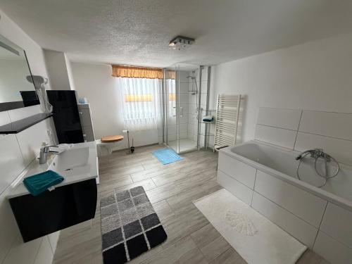 a white bathroom with a tub and a shower at Ferienwohnung Lippmann in Großhartmannsdorf