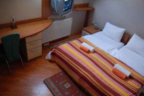 a bedroom with a desk and a bed with a striped blanket at Car Royal Apartments and Rooms in Novi Sad