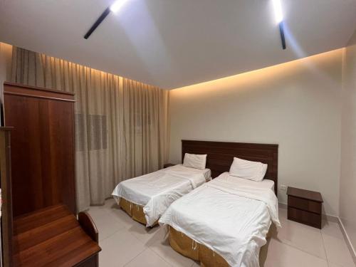 two beds in a hotel room with white sheets at شقق ضيافه خاصه 5391 in Yanbu