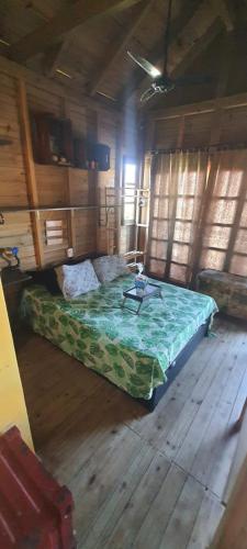 a bedroom with a bed in a room with wooden floors at Cabana Rústica Praia do Sonho in Palhoça