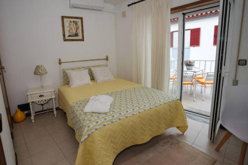 a bedroom with a bed and a balcony with a table at Casa Aguarela in São Romão