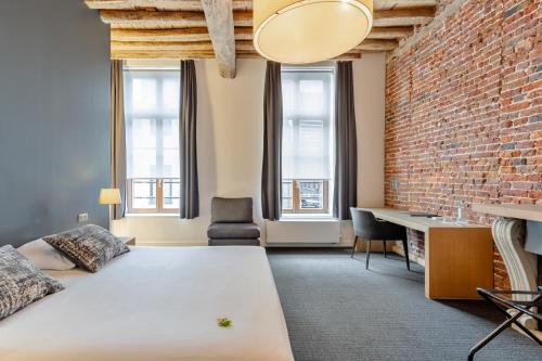 a bedroom with a bed and a brick wall at Hotel De Groene Hendrickx in Hasselt