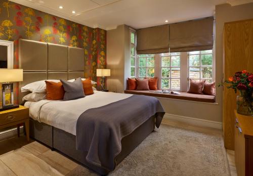 a bedroom with a large bed and a window at Langshott Manor - Luxury Hotel Gatwick in Horley