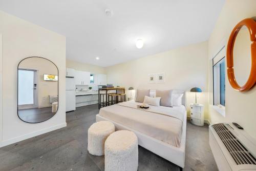 a white bedroom with a large bed and a mirror at El Jardin by Renzzi in Miami