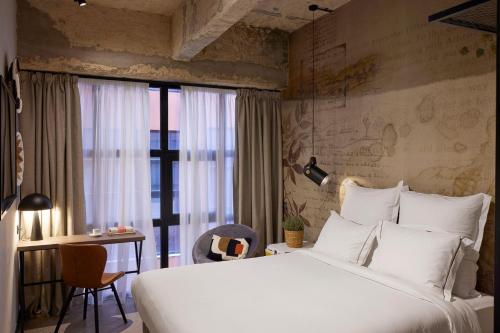 a bedroom with a large white bed and a desk at Anise Aluma Athens, Tapestry Collection by Hilton in Athens