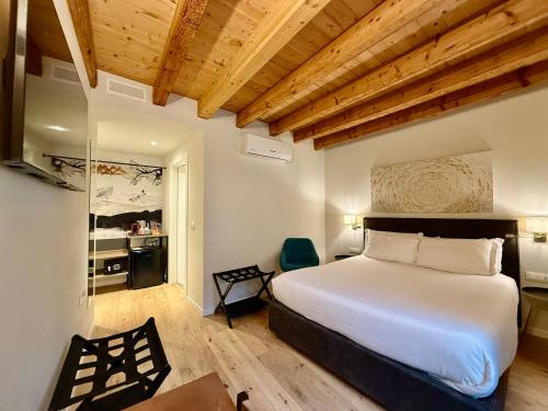a bedroom with a large white bed and a chair at Malvezzi24 Boutique Rooms in Desenzano del Garda