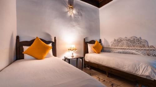 two beds in a room with yellow pillows at Riad Alassala Fes in Fez